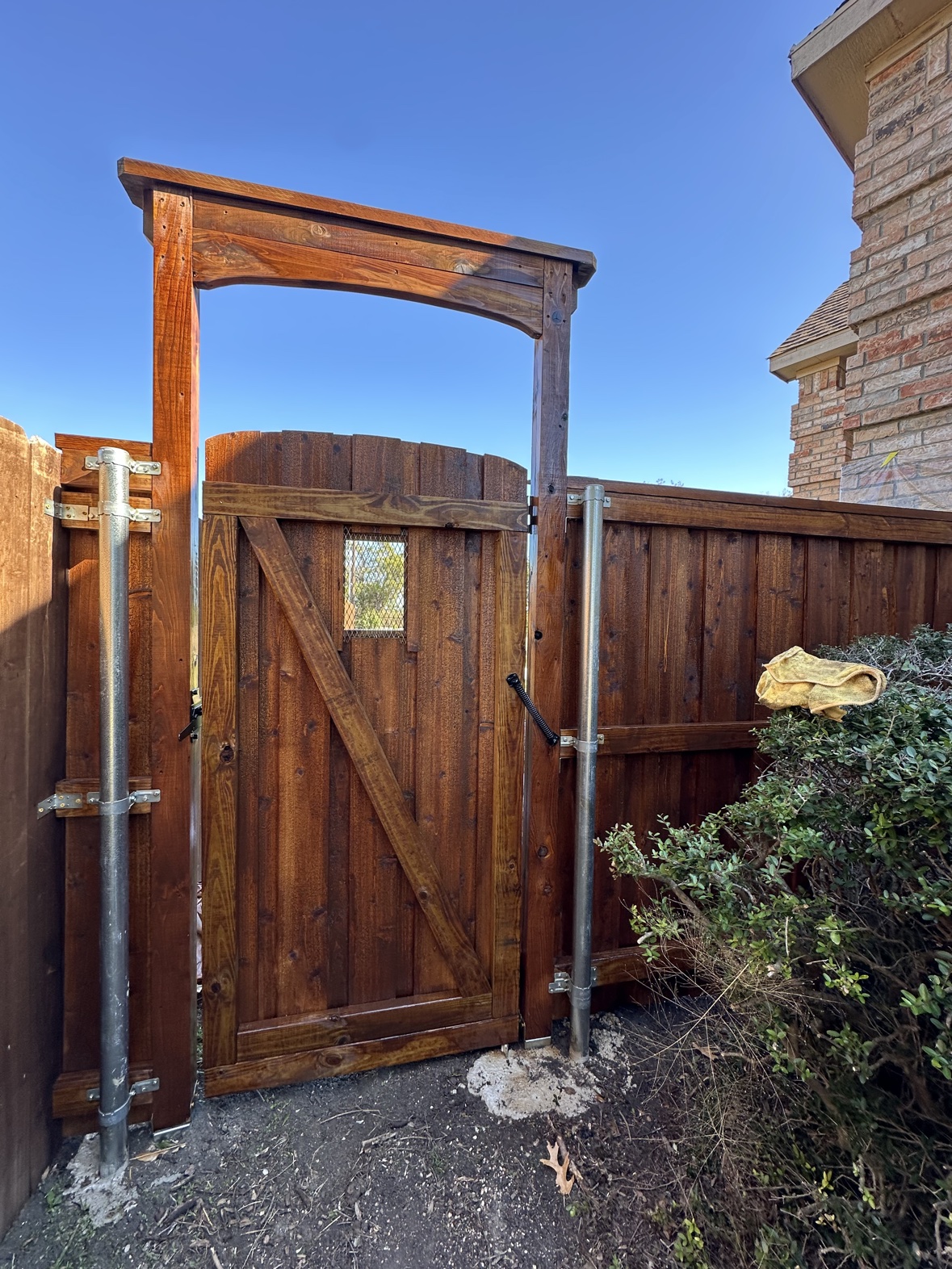 Custom arched-top stained wood driveway gate in Heath TX by Terra Renovations