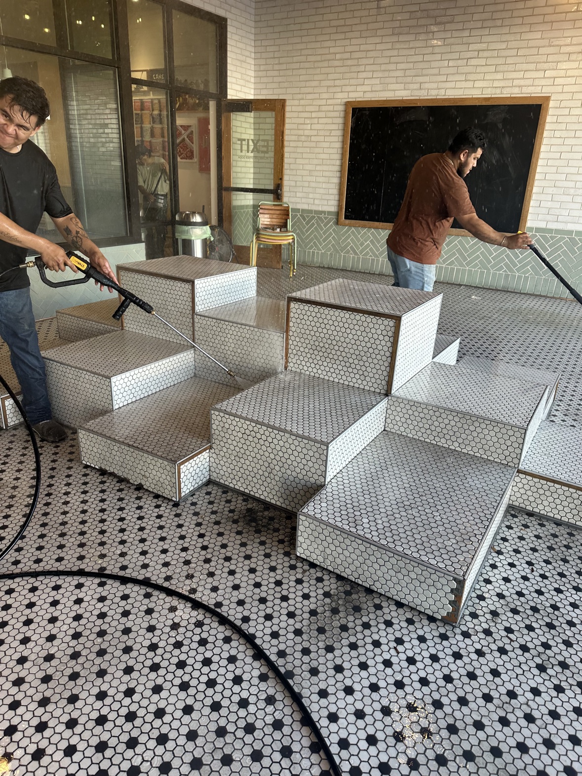 Two workers pressure washing tiled seating area, commercial pressure washing Dallas