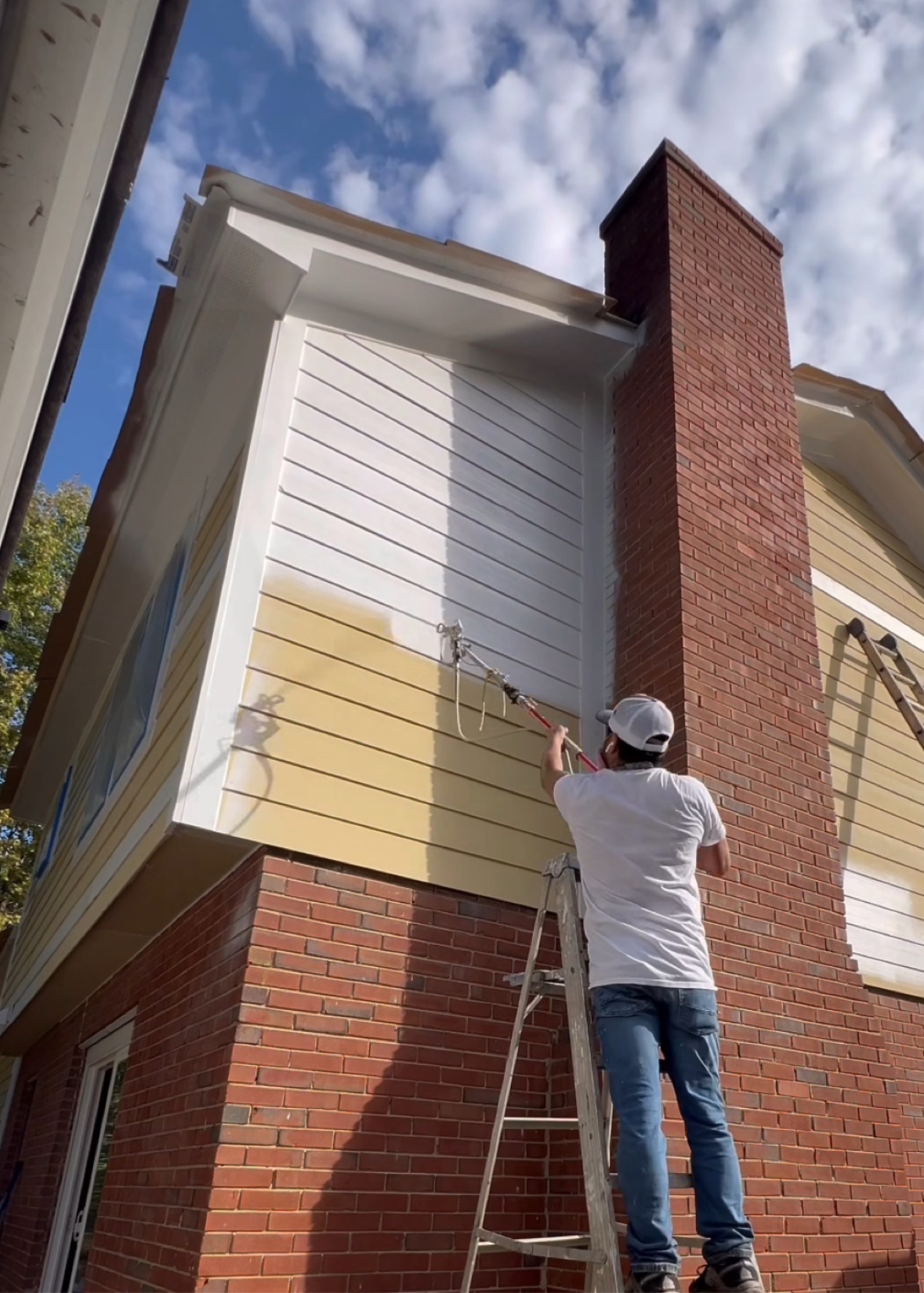 Spraying fresh paint on repaired home exterior siding, DFW exterior restoration