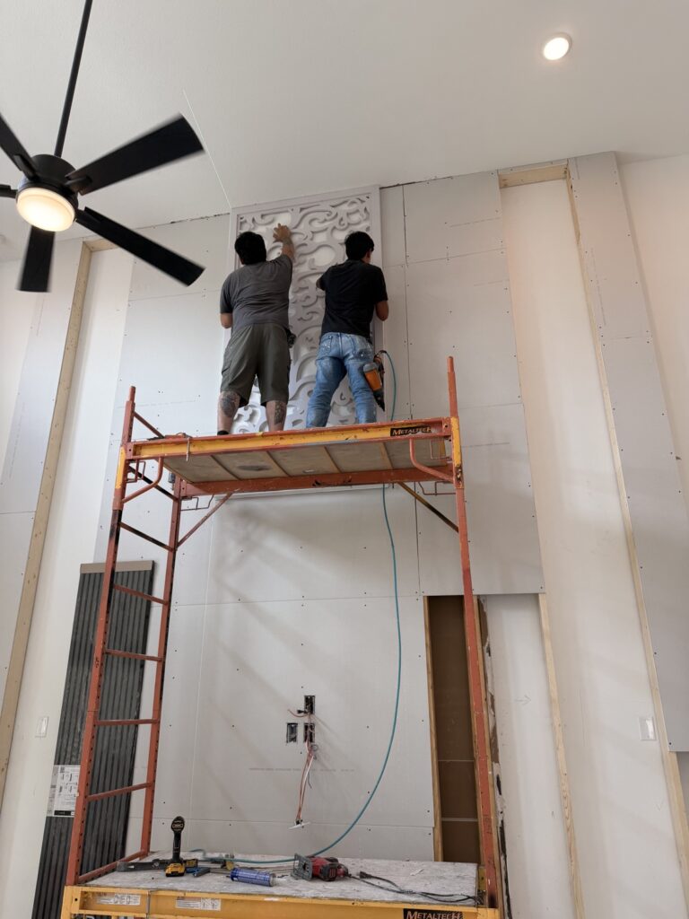 Workers on scaffolding installing a decorative 3D accent wall by Terra Renovations, Dallas-Fort Worth general contractor