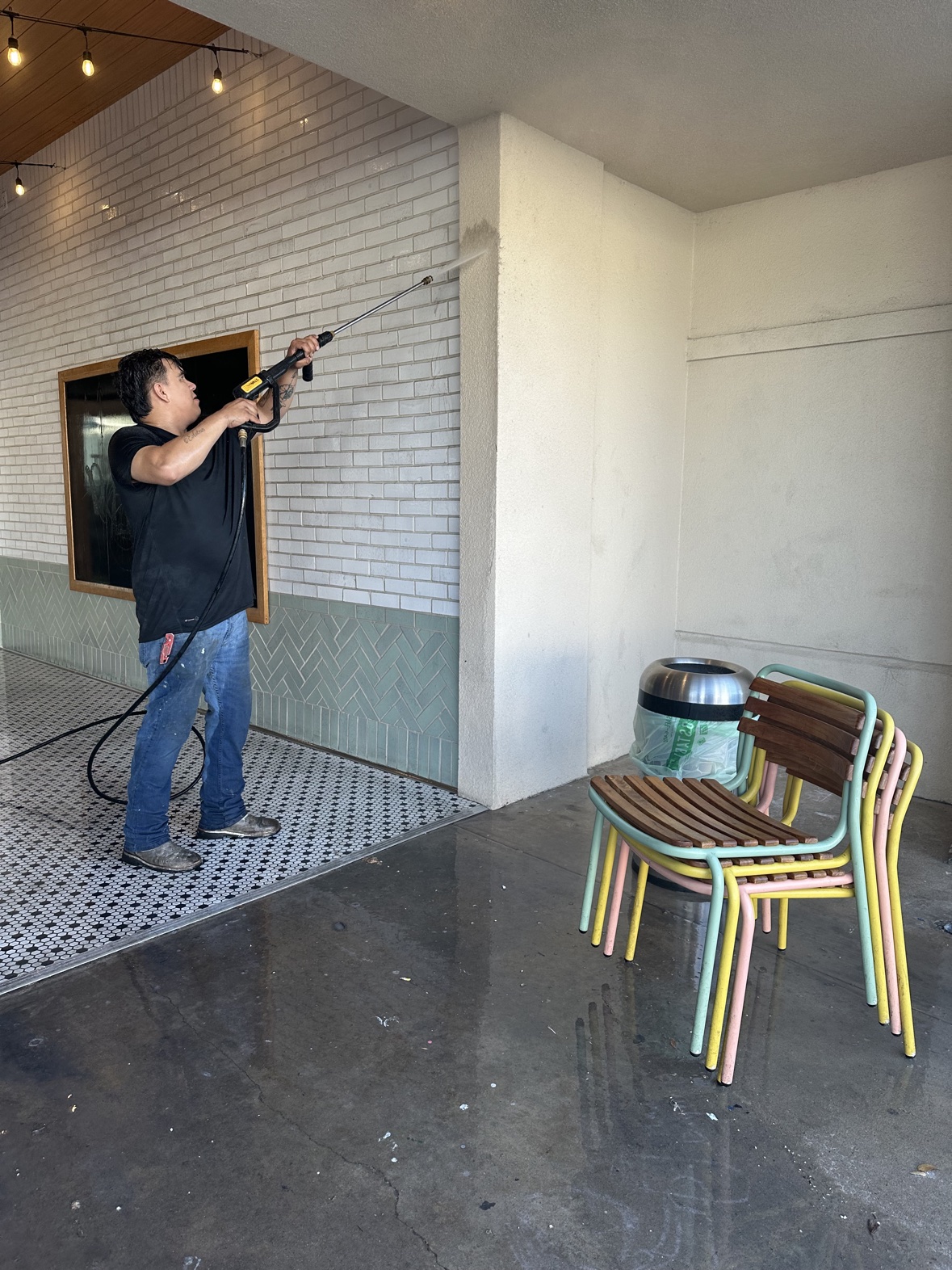 Worker soft washing exterior wall and column, house washing Dallas TX by Terra Renovations
